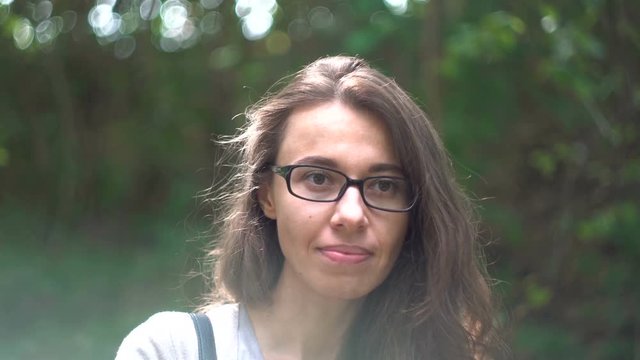 Beautiful young woman posing against a waterfall background. Slow motion