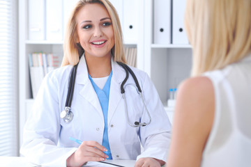 Doctor and  patient  discussing something while sitting at the table . Medicine and health care concept