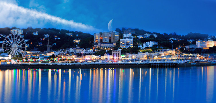 Torquay Promenade with the moon in the distance and lights reflecting in the sea