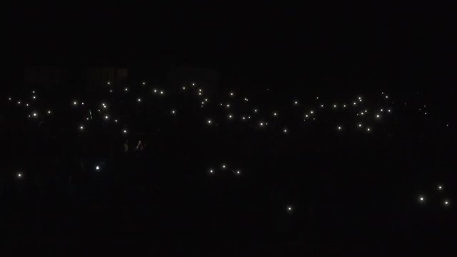 People shining flashlights. Crowd of people shining screens of telephones. Concert Crowd With Cell Phone Lights