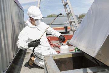 professional in protective uniform, mask, gloves in the roof for cleaning