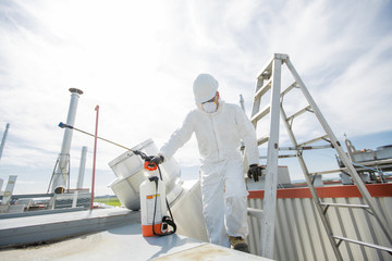 professional in protective uniform, mask, gloves in the roof for cleaning