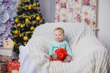 Lovely little baby girl playing in the winter on the floor near the Christmas tree on the Christmas holidays, studio shot.