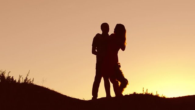 Couple in love kiss neck walking sunset on silhouette nature slow motion video. Man and woman silhouette of love walk with a dog