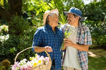 Senior couple walking in garden with flower basket 