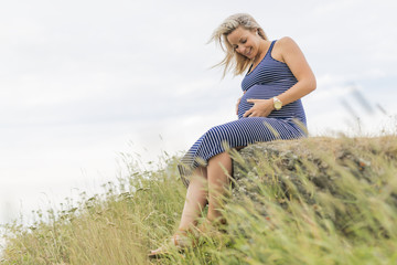 Portrait of a young beautiful blond pregnant woman on the side of the beach