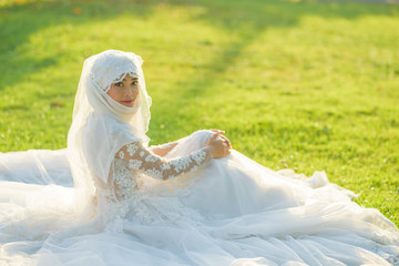 Portrait of a beautiful muslim bride with make up in white wedding dress with beautiful white...