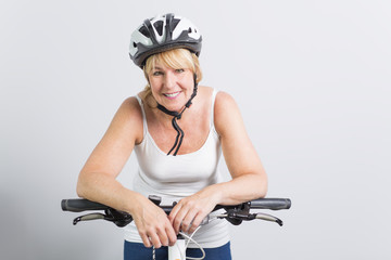 senior woman on the side of a bike in studio white background
