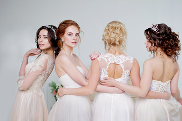 Bride in wedding salon. Four beautiful girl are in each other's arms. Back, close-up lace skirts