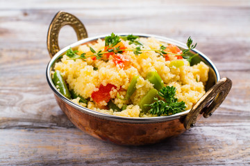 Couscouos Tabbouleh salad with tomatoes and kidney beans in a copper bowl on wooden table
