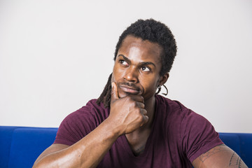 Handsome unsure, doubtful black man thinking, looking up with dubious expression on his face