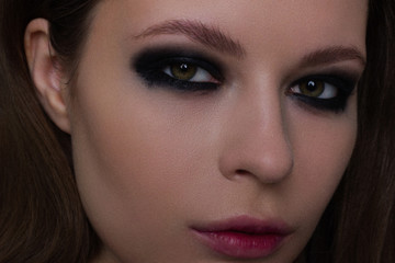 Close up of the woman with a languishing look and brown eyes. Gothic style, gloomy fashionable image. Smooth opaque skin, smoky eyes and natural lips