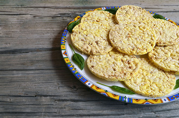 Whole grain crispbreads with spinach leaves on a plate on old wooden table.Puffed crispbreads.Rice and corn crispbreads.Healthy breakfast or diet concept.