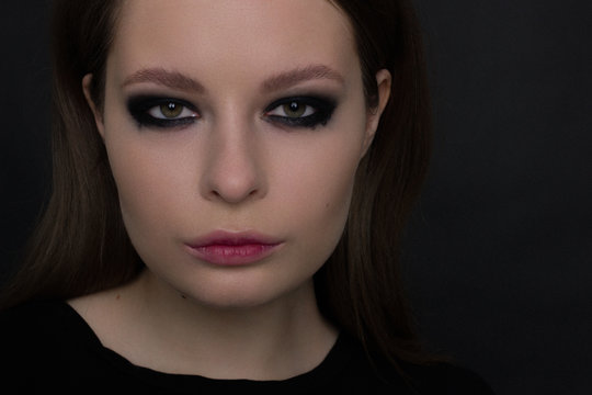 The beautiful woman with a languishing look and brown eyes. Gothic style, gloomy fashionable image. Smooth opaque skin, smoky eyes and natural lips