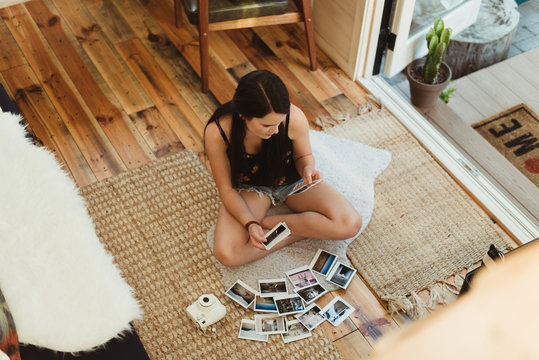 Young woman sits on floor of tiny home looking at pictures