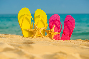 Fototapeta na wymiar Sea-stars with yellow and pink sandals stand in the sand against the background of the sea.