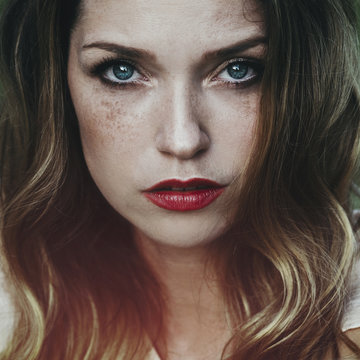 Artistic portrait of a beautiful young woman with freckles and blue eyes