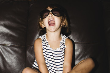 Funny little girl sitting on the couch screaming