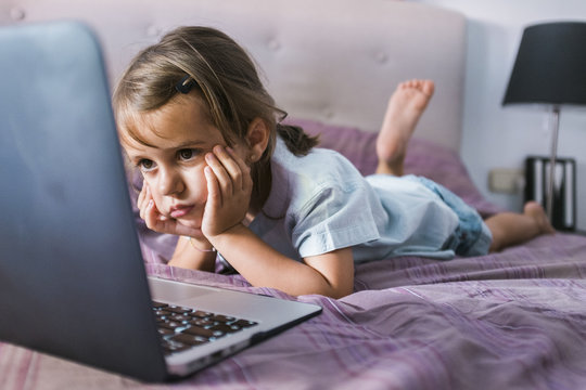 Girl in relaxed manner looking carefully at the screen of the laptop