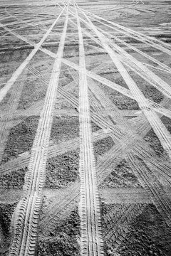 Grainy black and white of tire tracks on a beach