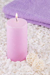 Obraz na płótnie Canvas Spa. Still life. Candle of pink color and towel on a background of white pebbles