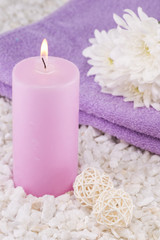 Obraz na płótnie Canvas Spa. Still life. Candle of pink color, a towel and white flowers on a background of white pebbles.