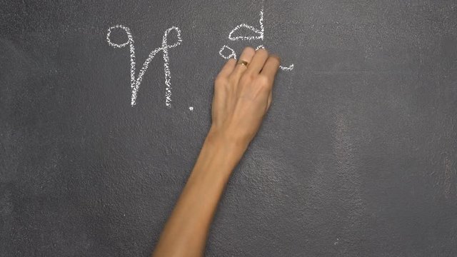 Woman's hand writing Thai letter "ห" with white chalk on blackboard