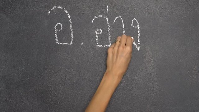 Woman's hand writing Thai letter "อ" with white chalk on blackboard