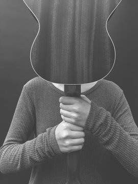 Teenage girl holding ukulele in front of face