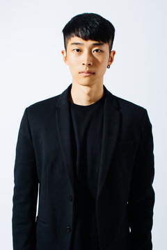Portrait of an attractive asian man wearing a black suit over white background.