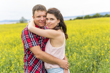 Happy smiling young couple over yellow green rape meadow