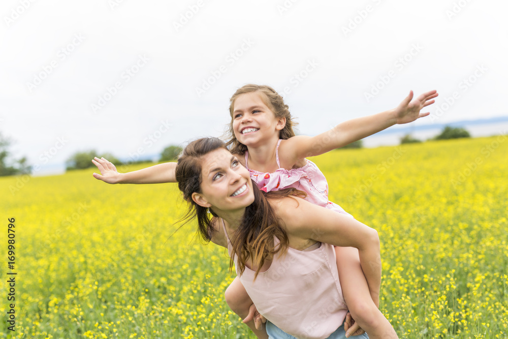 Wall mural happy family mother and child daughter embrace on yellow flowers on nature in summer