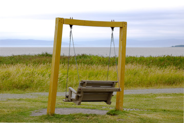 Fototapeta na wymiar Double swing by the sea at LaPocatiere, Quebec on a quiet day and a cloudy sky