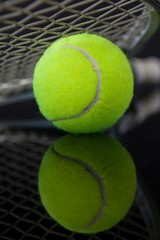 Close up of tennis racket on fluorescent yellow ball with