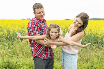Happy family couple nd child daughter on yellow flowers on nature in summer