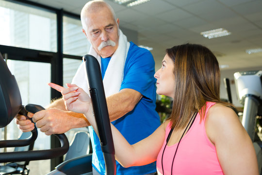 fitness instructor advising senior man using equipment