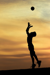 Fototapeta na wymiar Silhouette of boy leaping for ball.