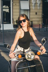 Fototapeta na wymiar Young happy stylish woman on vintage scooter in city centre 