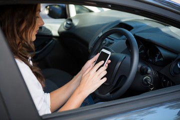 Obraz na płótnie Canvas Woman using mobile phone while driving a car