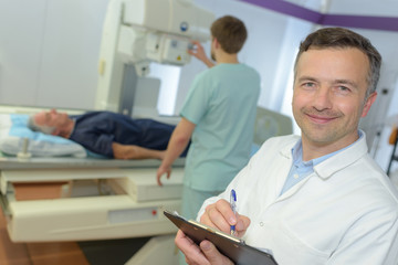 Obraz premium happy male doctor with clipboard writing prescription