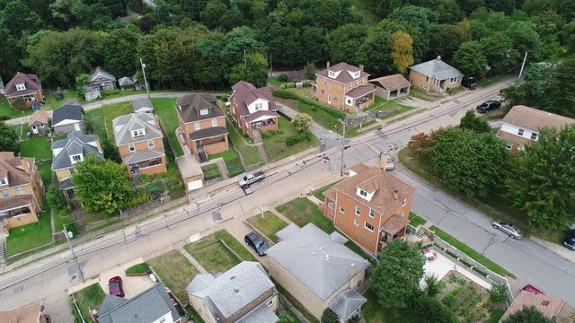 A slowly moving forward aerial view of a typical western Pennsylvania residential neighborhood corner.  	
