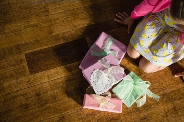 Girl sitting with gift boxes on wooden floor