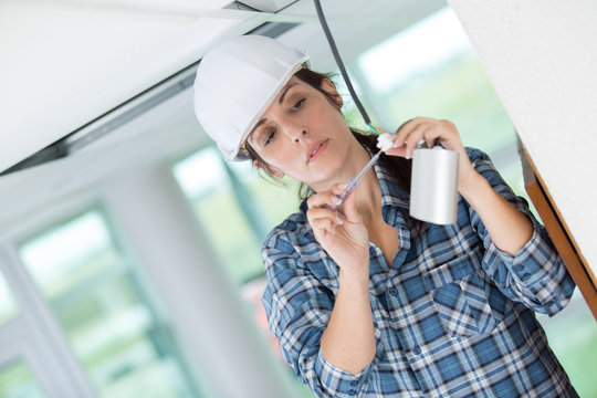 female electrician installing security camera