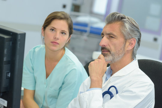 handsome doctor talking to pretty nurse about patients case