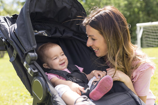 Portrait of beautiful young woman pushing baby carriage in the park