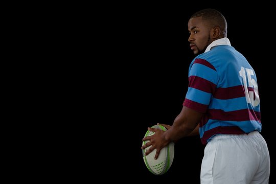 Side view of sportsman holding rugby ball while looking away