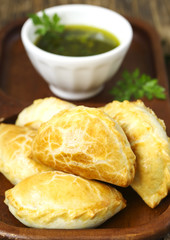 Empanadas with chimichurri sauce on wooden table