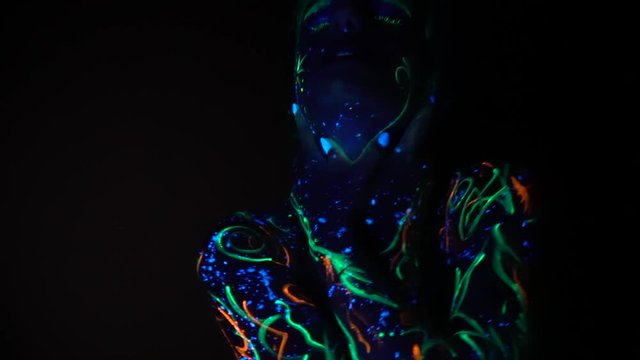 A girl painted with fluorescent paint grabs her neck and strangles herself in the dark