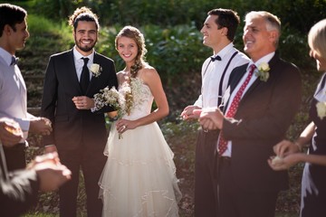 Portrait of bride and groom standing with guests - Powered by Adobe