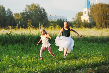 Two little girls having fun running on the field. Sisters are playing catching up with each other.